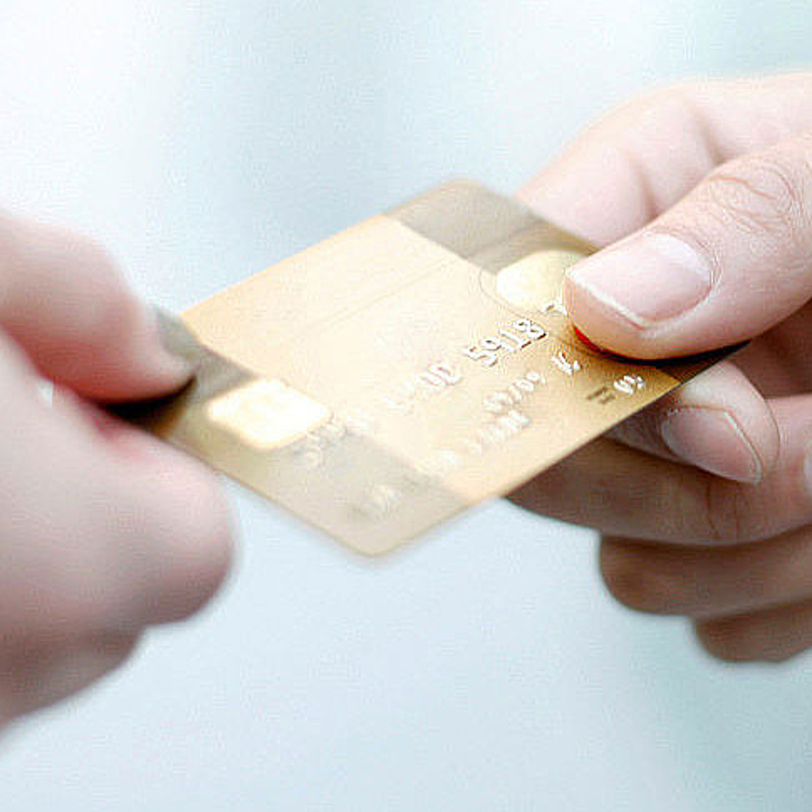 eine Hand nimmt eine Kreditkarte aus einer anderen Hand entgegen